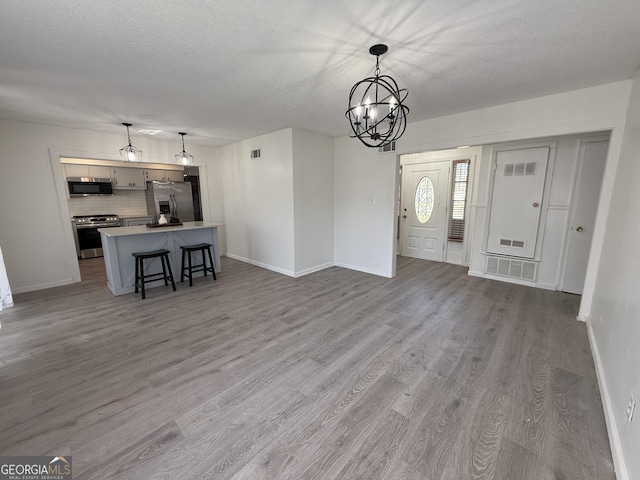 interior space featuring an inviting chandelier, wood finished floors, visible vents, and a textured ceiling