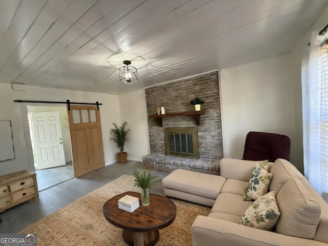 living area featuring wood finished floors, baseboards, wood ceiling, a barn door, and a brick fireplace