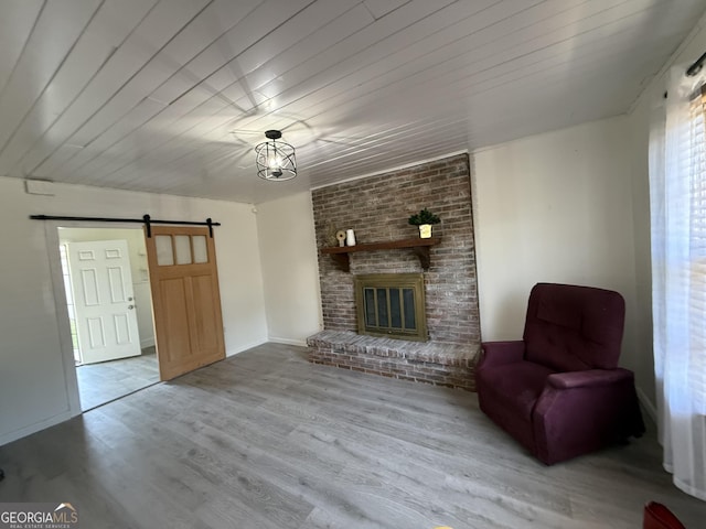 living area featuring a fireplace, wooden ceiling, a barn door, and wood finished floors