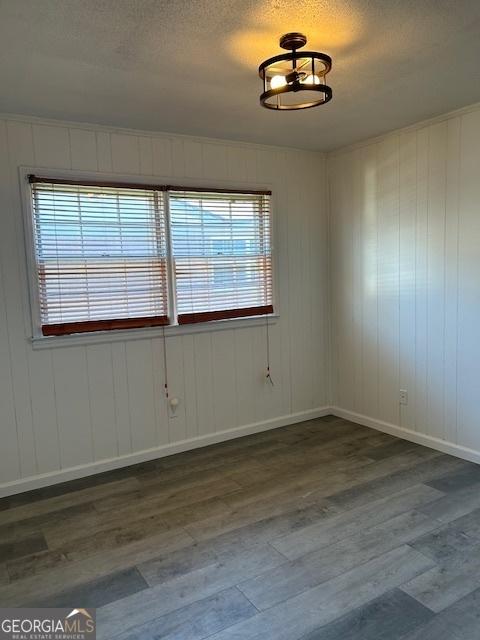 empty room with wood finished floors, baseboards, and a textured ceiling