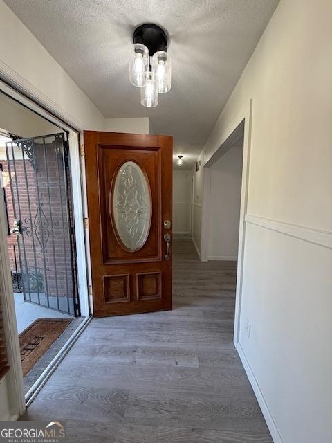 foyer with a textured ceiling, baseboards, and wood finished floors