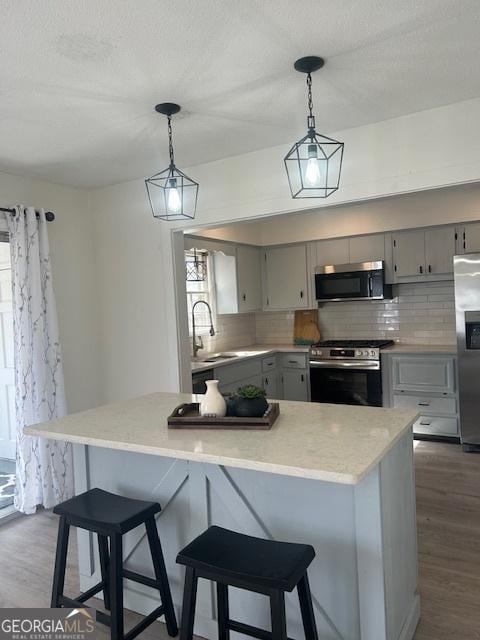 kitchen with dark wood finished floors, light countertops, gray cabinets, appliances with stainless steel finishes, and a sink