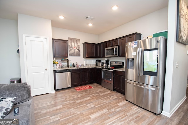 kitchen featuring visible vents, light stone countertops, dark brown cabinetry, light wood-type flooring, and stainless steel appliances