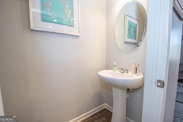 bathroom with a sink, baseboards, and wood finished floors