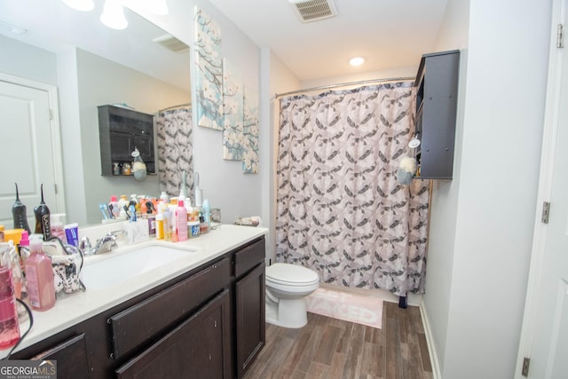 full bath with visible vents, toilet, a shower with curtain, wood finished floors, and vanity