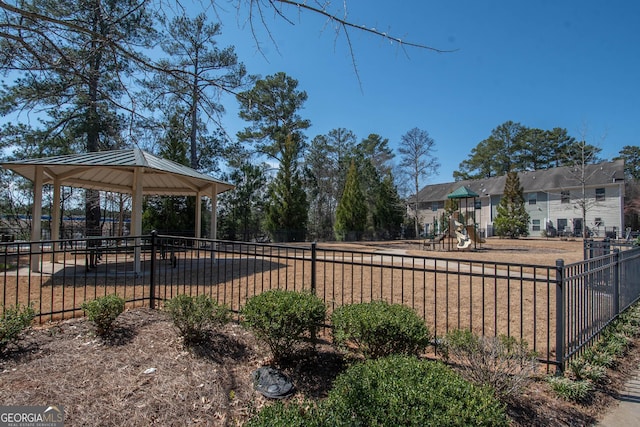 view of yard featuring a gazebo, playground community, and fence