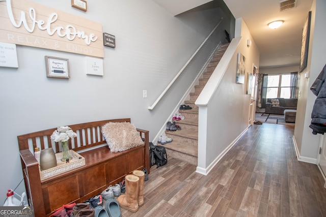 interior space featuring visible vents, baseboards, wood finished floors, and stairs