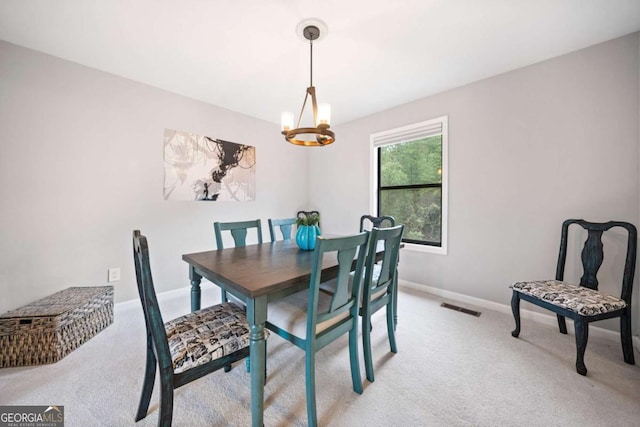 dining room with a notable chandelier, light colored carpet, visible vents, and baseboards