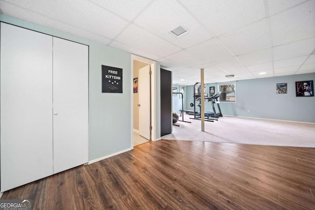 exercise area featuring visible vents, wood finished floors, baseboards, and a paneled ceiling