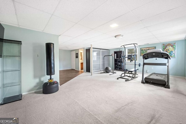 workout area featuring a drop ceiling, baseboards, and carpet