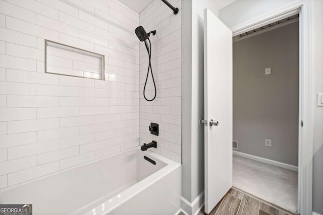 bathroom with visible vents, wood finished floors, baseboards, and shower / bath combination