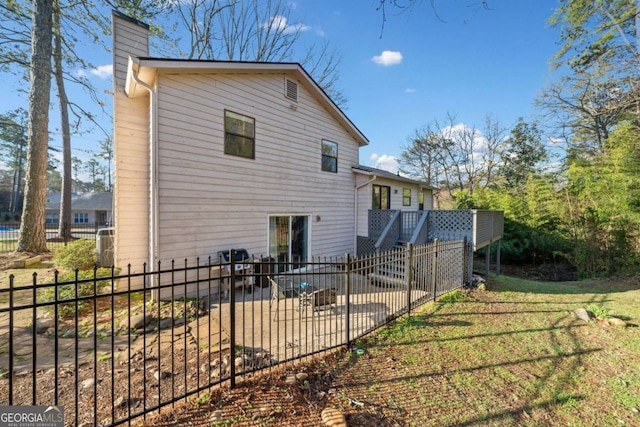 back of property with a patio, a lawn, a chimney, and fence