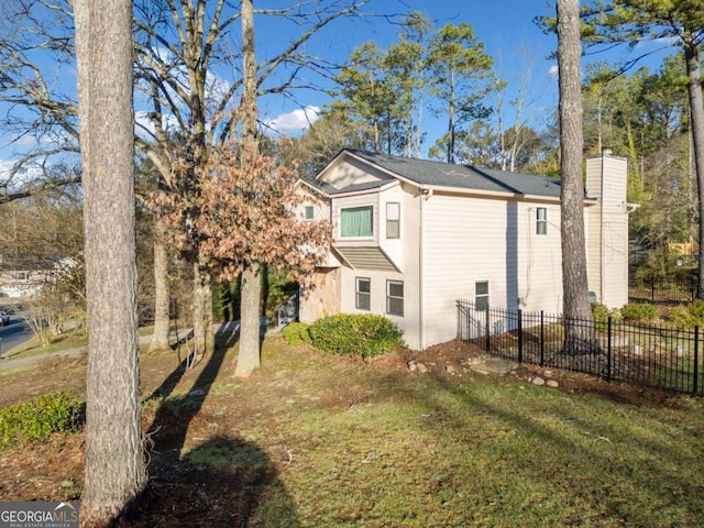 exterior space with a lawn, a chimney, and fence