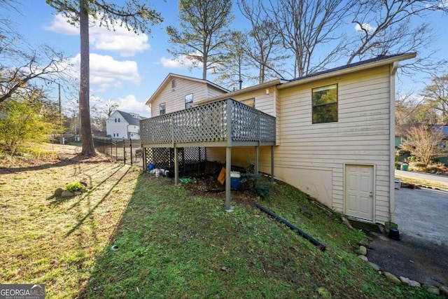 rear view of property with a deck, a yard, and fence