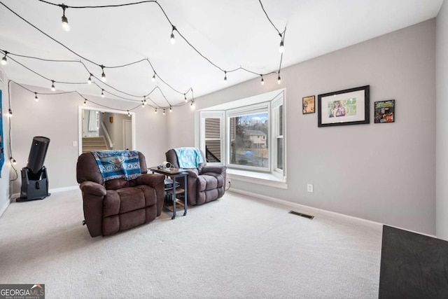 living area with visible vents, baseboards, carpet, and stairs