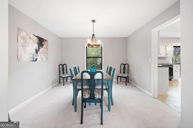 dining space featuring baseboards, plenty of natural light, an inviting chandelier, and light carpet