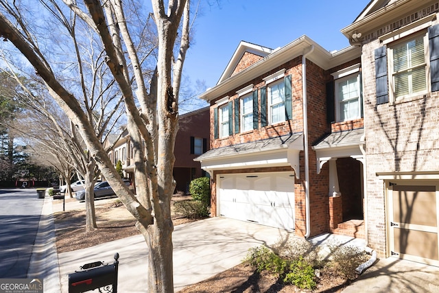 townhome / multi-family property featuring concrete driveway, a garage, and brick siding