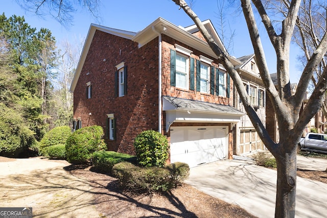 view of property exterior with brick siding, an attached garage, concrete driveway, and fence