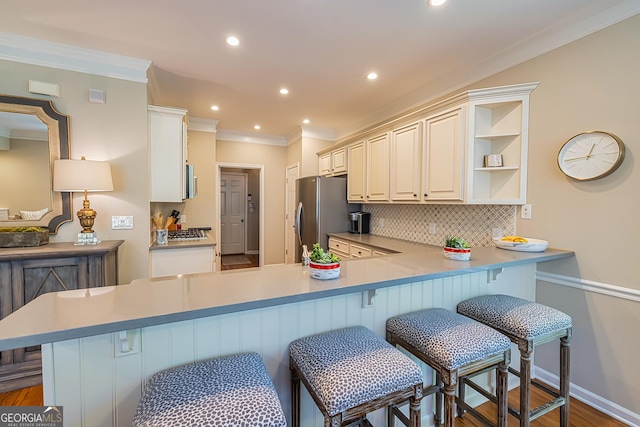 kitchen featuring a kitchen bar, backsplash, freestanding refrigerator, and open shelves