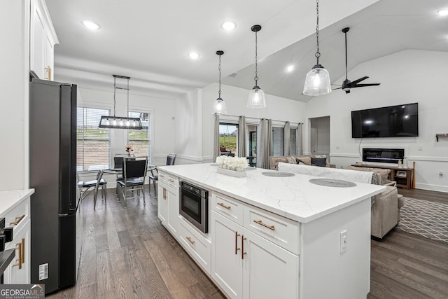 kitchen with dark wood-type flooring, a kitchen island, white cabinetry, freestanding refrigerator, and built in microwave