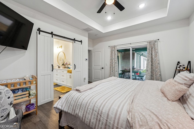 bedroom featuring access to exterior, visible vents, a barn door, wood finished floors, and a raised ceiling