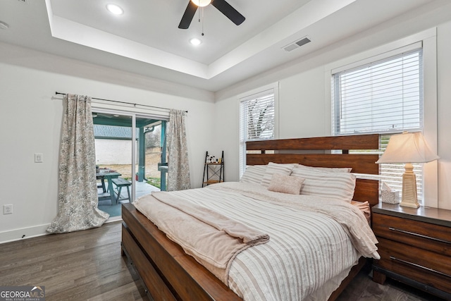 bedroom with access to exterior, visible vents, baseboards, wood finished floors, and a raised ceiling