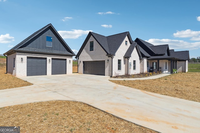 modern farmhouse with brick siding, board and batten siding, an attached garage, and driveway