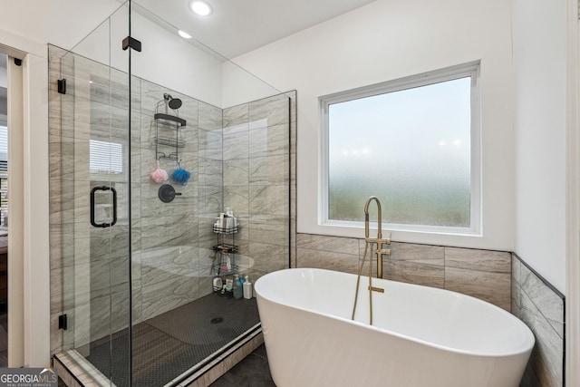 full bathroom with recessed lighting, a stall shower, a freestanding bath, and tile walls