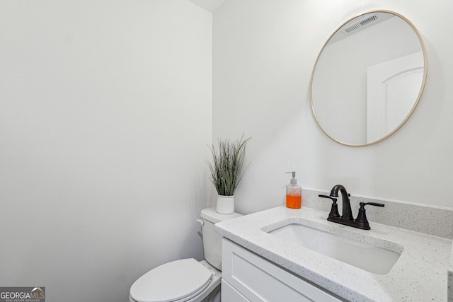 half bath with visible vents, toilet, and vanity