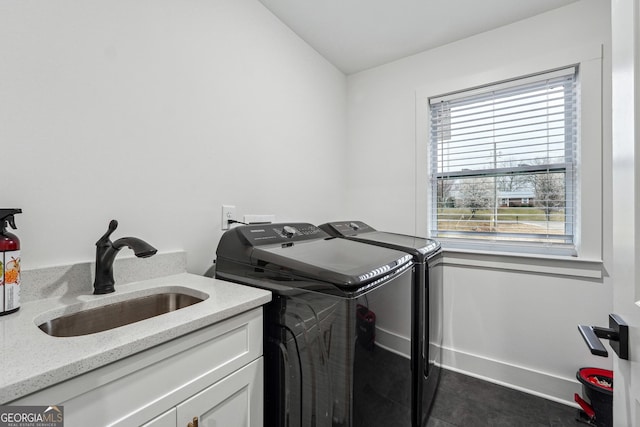 washroom with cabinet space, separate washer and dryer, baseboards, and a sink