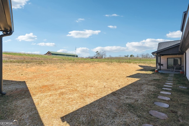 view of yard with a rural view and fence