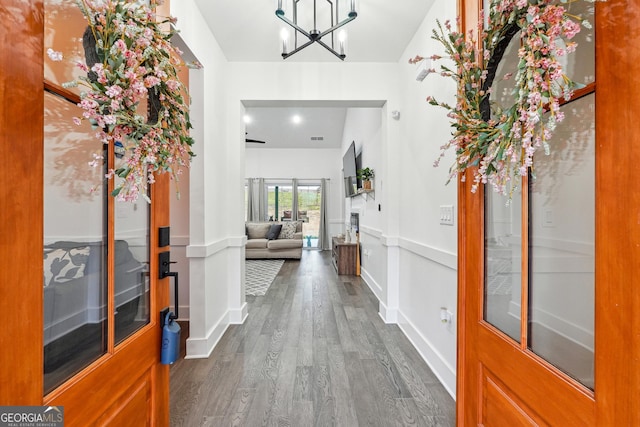 entrance foyer with visible vents, a notable chandelier, dark wood-style floors, and baseboards