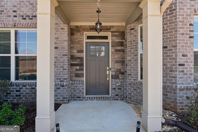 view of exterior entry with brick siding and covered porch