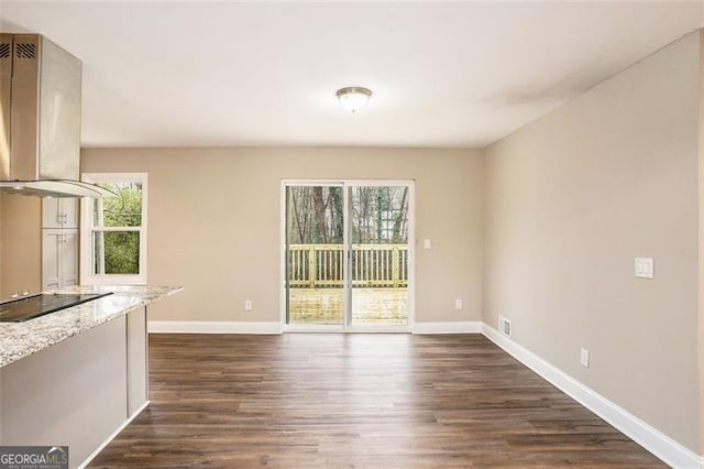 unfurnished living room featuring dark wood finished floors, a healthy amount of sunlight, and baseboards