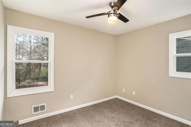 carpeted spare room with visible vents, ceiling fan, and baseboards