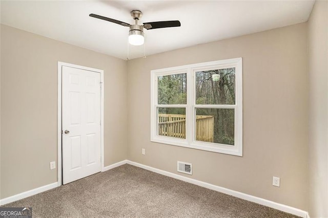 spare room with visible vents, dark carpet, baseboards, and ceiling fan