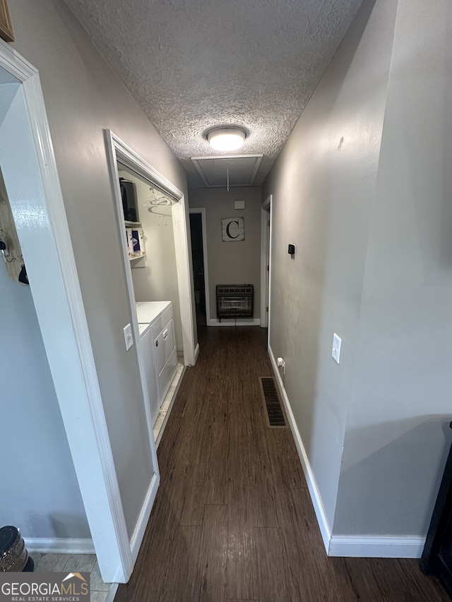 corridor with visible vents, heating unit, attic access, dark wood-style flooring, and washing machine and clothes dryer