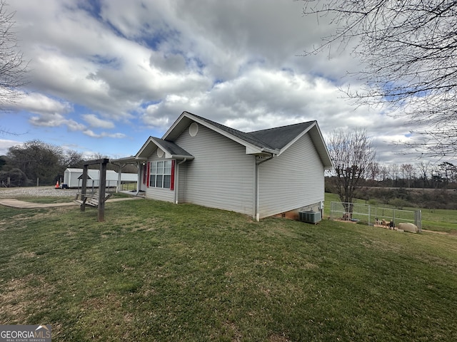 view of side of property with a lawn, central AC unit, and fence