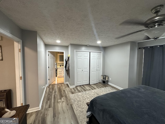 bedroom featuring a closet, a textured ceiling, baseboards, and wood finished floors