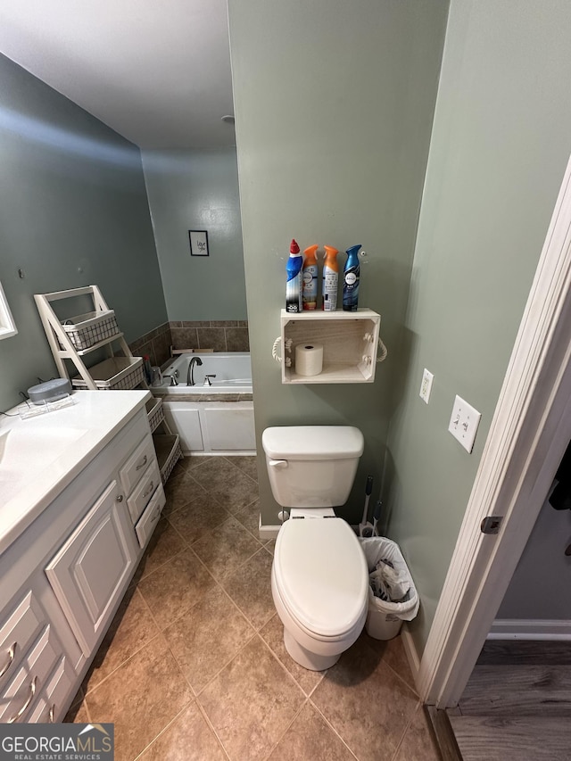full bathroom with tile patterned floors, toilet, baseboards, a bath, and vanity