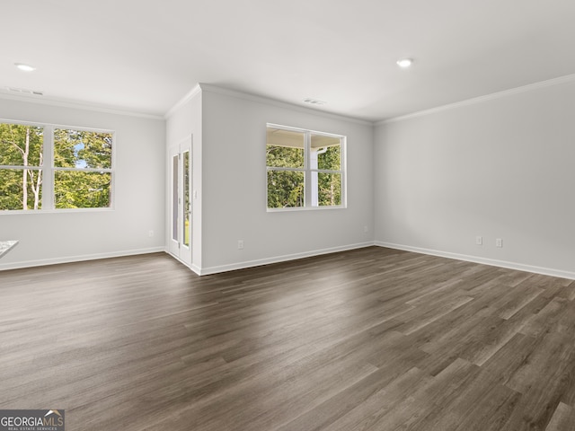 spare room featuring visible vents, dark wood-type flooring, baseboards, and ornamental molding