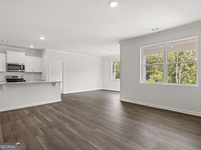 unfurnished living room featuring visible vents, baseboards, dark wood-style floors, and ornamental molding