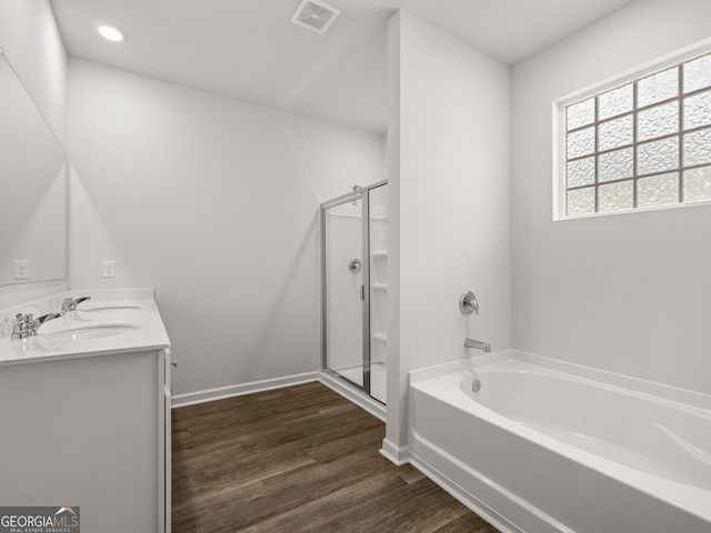 bathroom with visible vents, a garden tub, a stall shower, wood finished floors, and double vanity