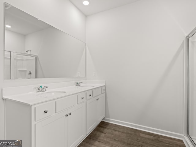 full bathroom featuring wood finished floors, a shower with shower door, and a sink