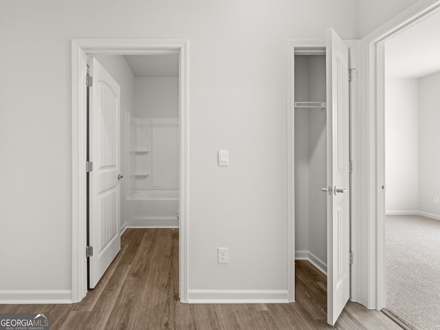 unfurnished bedroom featuring a closet, baseboards, wood finished floors, and a spacious closet