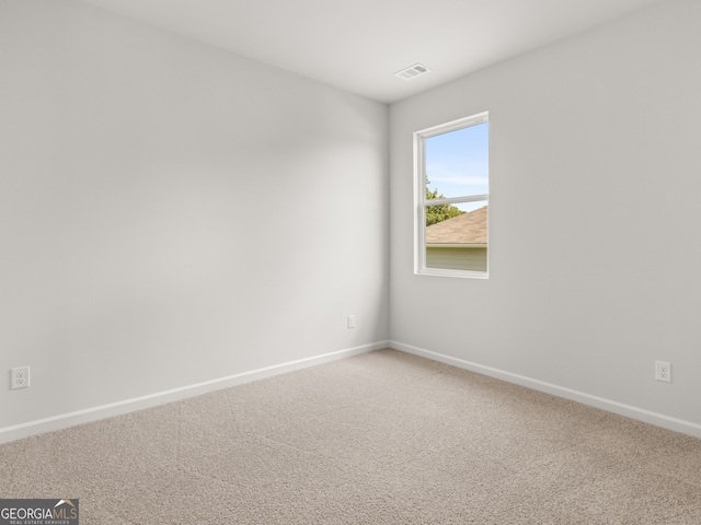 empty room with light colored carpet, visible vents, and baseboards