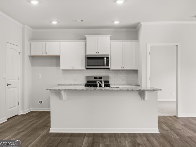 kitchen featuring visible vents, an island with sink, a sink, stainless steel appliances, and white cabinetry