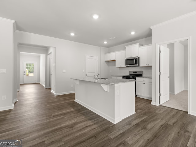 kitchen with dark wood finished floors, an island with sink, appliances with stainless steel finishes, white cabinets, and a sink