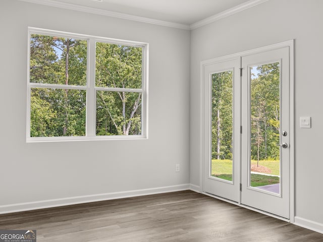 doorway to outside featuring crown molding, wood finished floors, baseboards, and a wealth of natural light