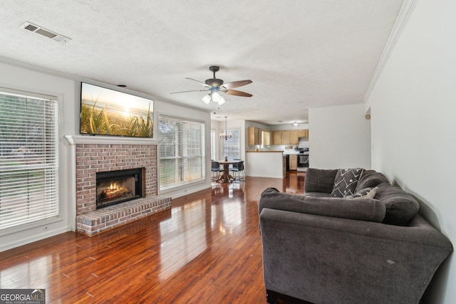 living room featuring visible vents, dark wood-type flooring, ceiling fan with notable chandelier, a textured ceiling, and a healthy amount of sunlight